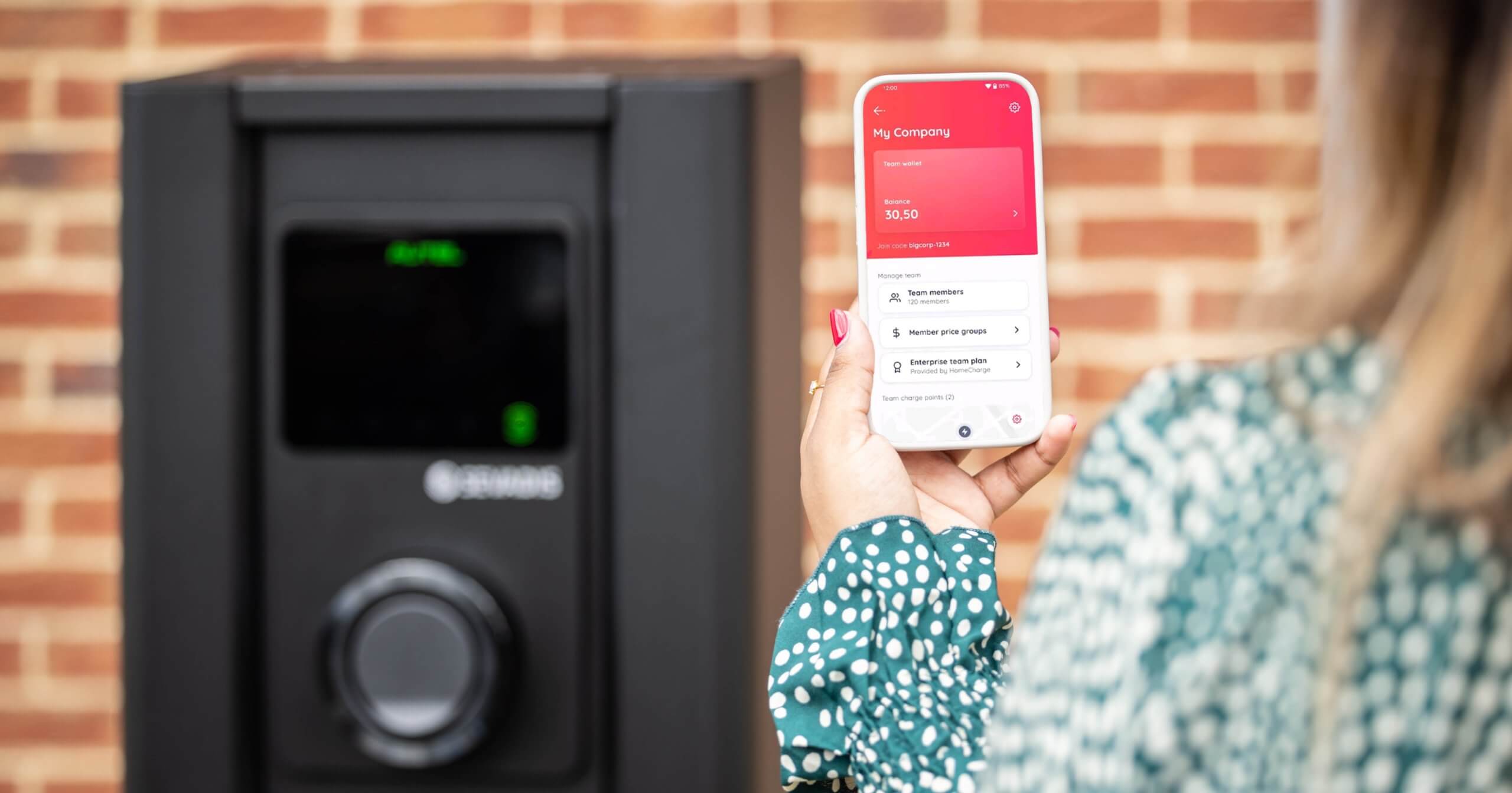 woman using an app to charge her EV at a MaxiCharger pillar